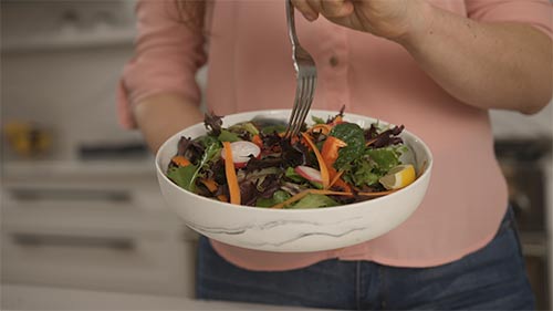 woman eating a salad in a modern kitchen