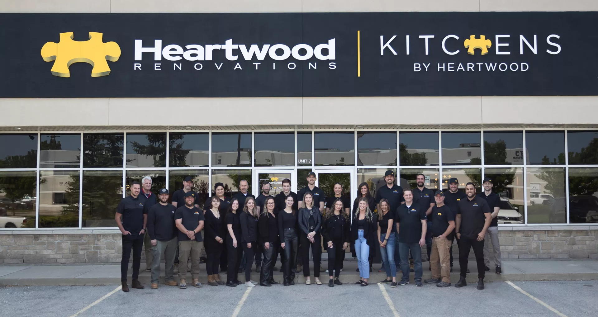 The Heartwood Renovations team standing in front of a building with signage for Heartwood Renovations and Kitchens by Heartwood.